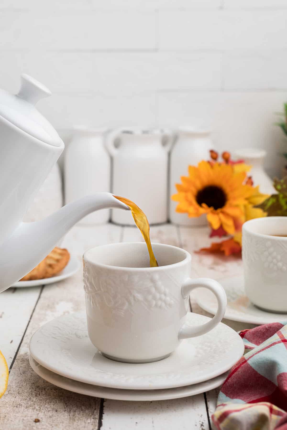 Spiced tea being poured from a pitcher into a cup.