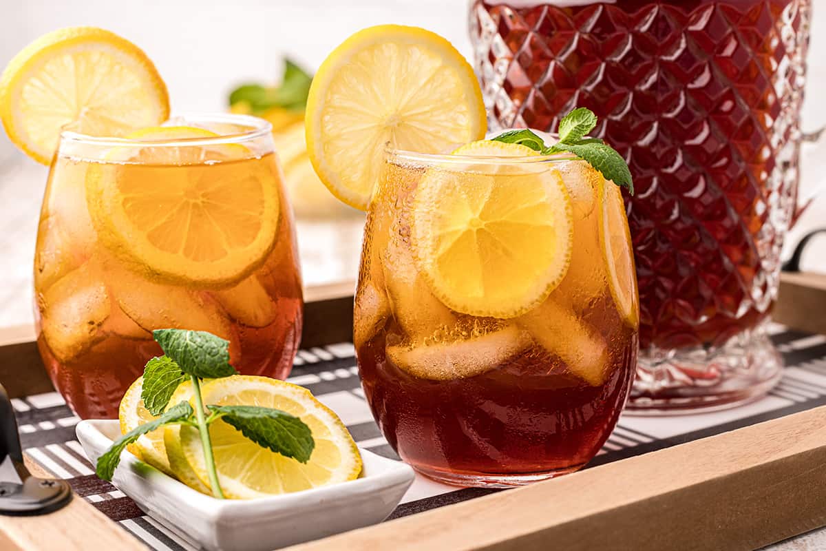 A glass of southern iced sweet tea with lemon and mint on a serving tray.