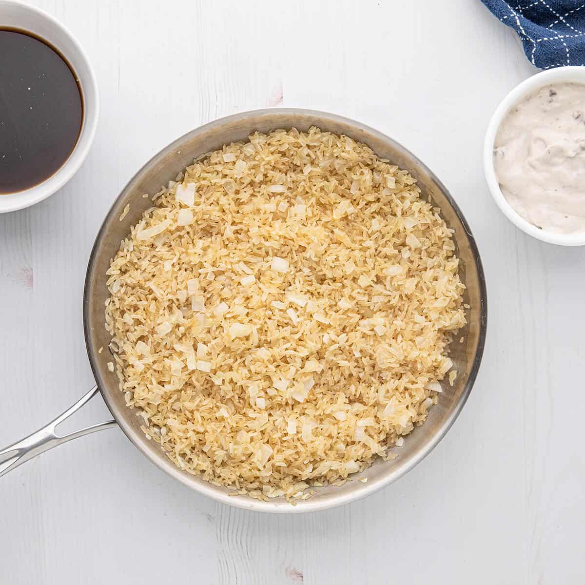 Browned rice and onions in a skillet.