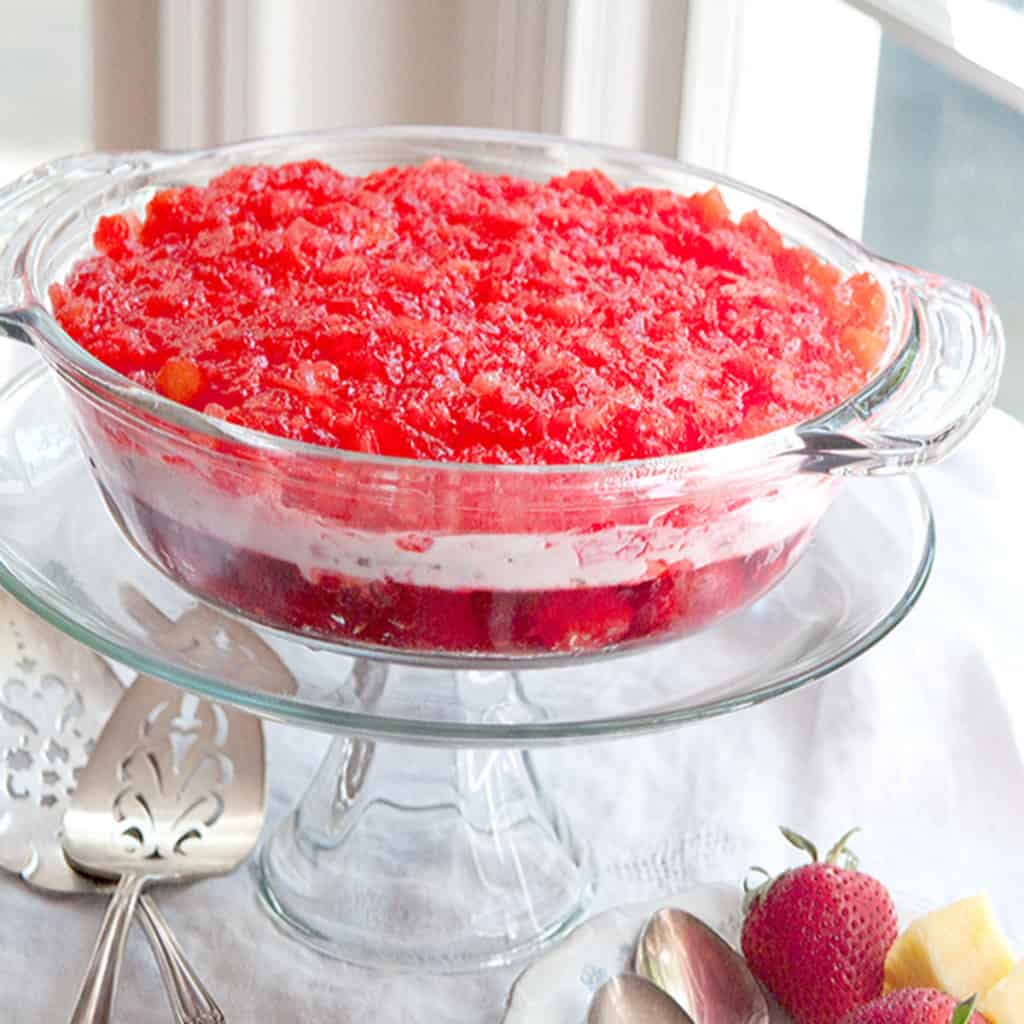 Strawberry banana jello mold on a glass pedestal.