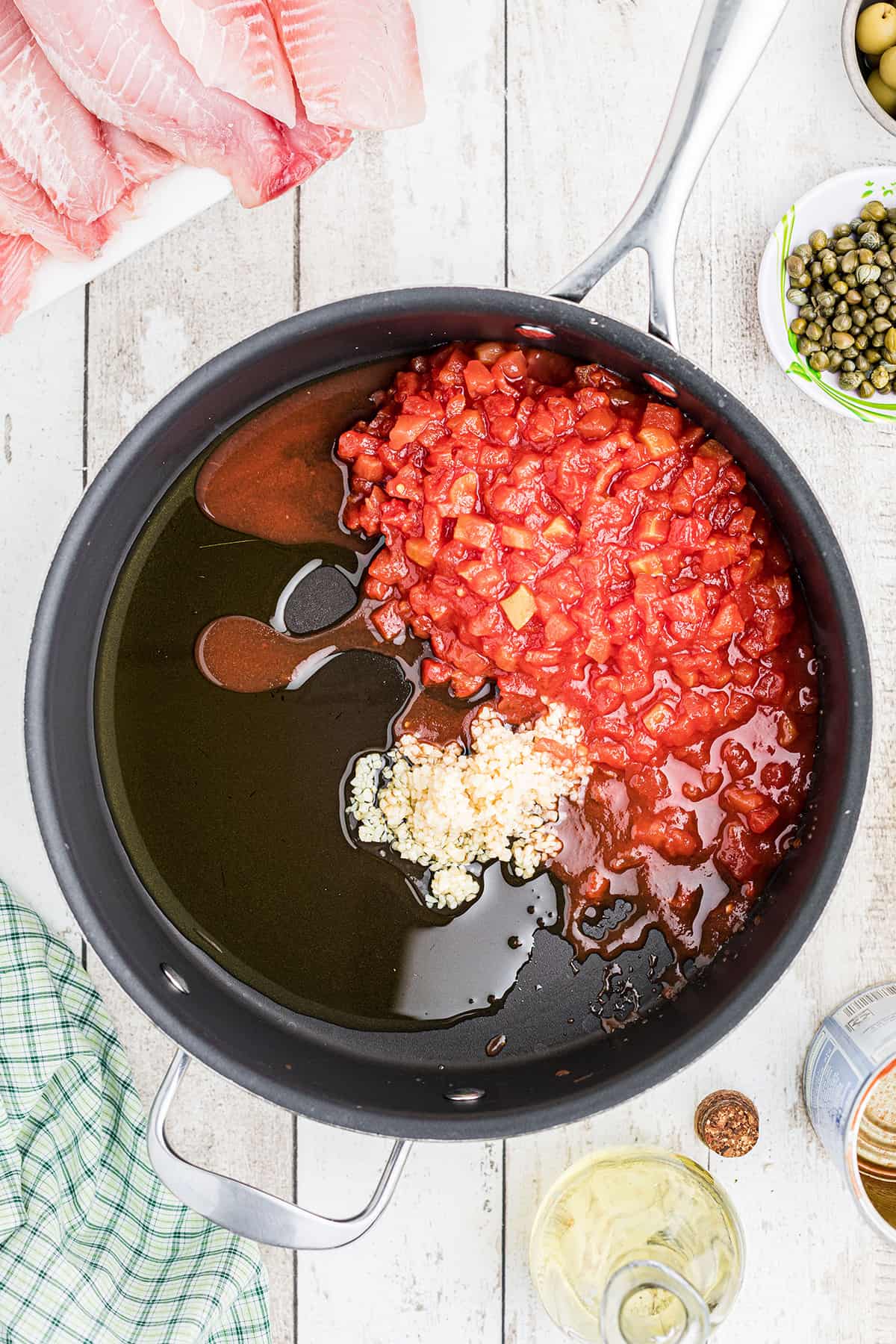 Garlic, olive oil, and tomatoes in a skillet.