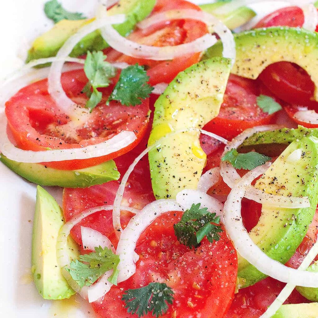 Tomato and avocado salad on a large white serving plate.