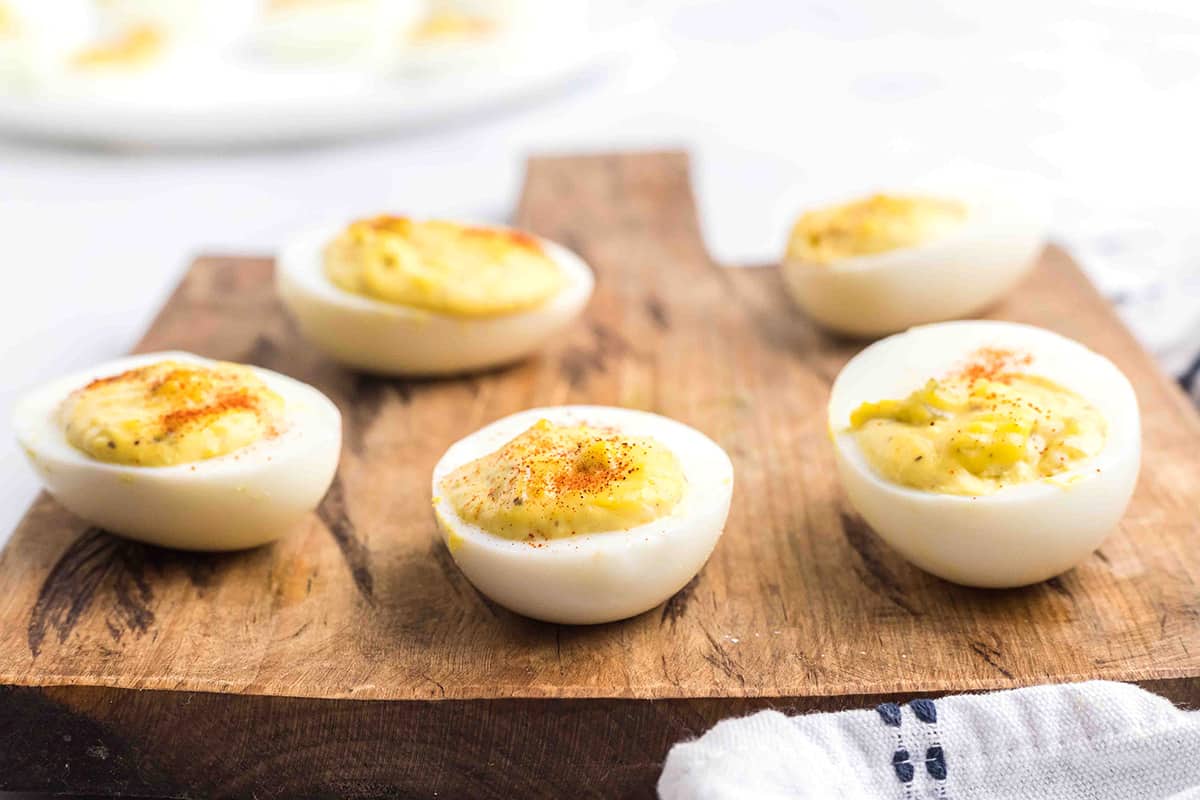 Finished deviled eggs on a wooden board.